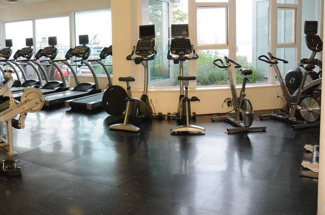 Bright and spacious gym with treadmills and stationary bikes, large windows offering a view of the city.