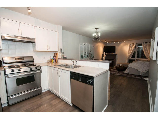 Bright kitchen with white cabinets, stainless steel appliances, and hardwood floors. - 106 - 1868 W. 5th Avenue, Vancouver West Side