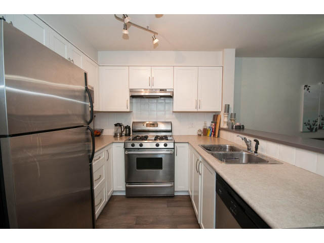 Bright kitchen with white cabinets, stainless steel appliances, and granite countertops. - 106 - 1868 W. 5th Avenue, Vancouver West Side