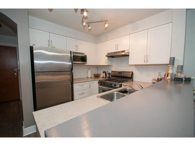 Bright kitchen with modern stainless steel appliances, white cabinets, and granite countertops. - 106 - 1868 W. 5th Avenue, Vancouver West Side