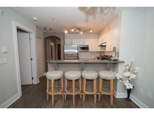 Bright kitchen with white cabinets, hardwood floors, and a bar counter. - 106 - 1868 W. 5th Avenue, Vancouver West Side