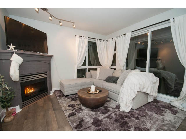 Furnished living room with hardwood floors, cozy fireplace, and large windows. - 106 - 1868 W. 5th Avenue, Vancouver West Side