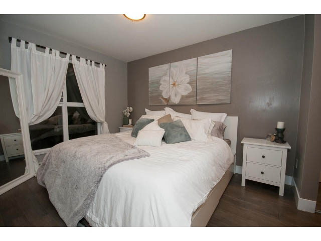 Furnished 1-bedroom + den with hardwood floors, white bedding, and a large window with curtains. - 106 - 1868 W. 5th Avenue, Vancouver West Side
