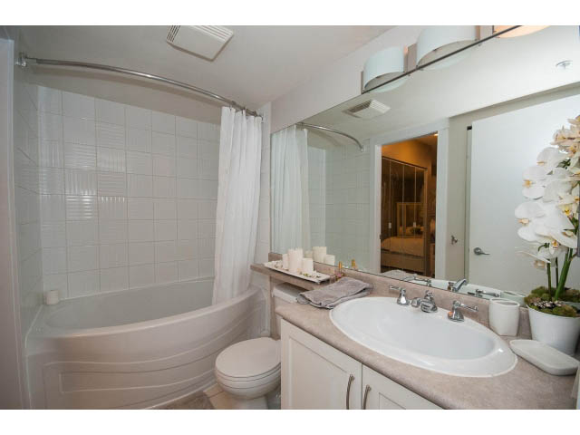 Furnished bathroom with white tile, large mirror, and modern sink. - 106 - 1868 W. 5th Avenue, Vancouver West Side