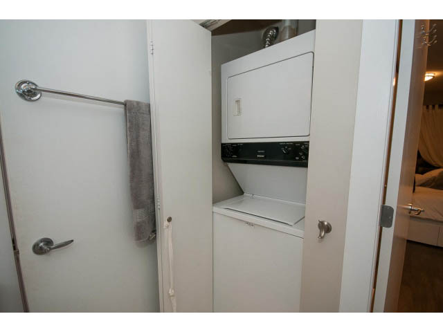 Bright laundry room with white cabinets and countertop, adjacent to a small kitchen area. - 106 - 1868 W. 5th Avenue, Vancouver West Side