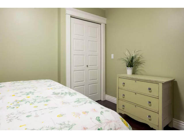 Furnished bedroom with floral bedding and light green walls. - 188 West 23rd Ave, Vancouver West Side