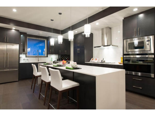 Bright kitchen with modern black cabinets, stainless steel appliances, and a city view through the window. - 3192 Beverley Cres, North Vancouver