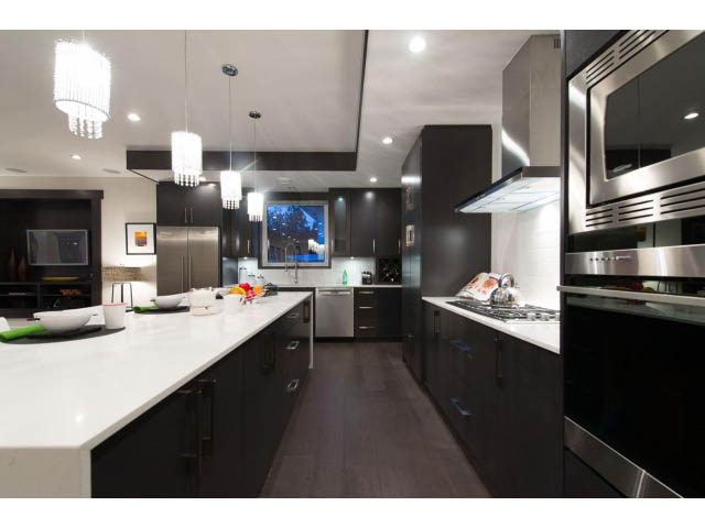 Bright kitchen with modern black cabinetry, white countertops, and hardwood floors. - 3192 Beverley Cres, North Vancouver