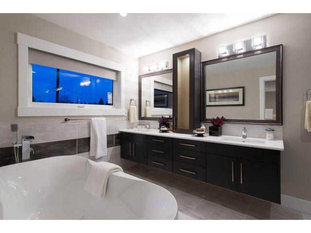 Spacious bathroom with dual sinks, large mirror, and city view window. - 3192 Beverley Cres, North Vancouver