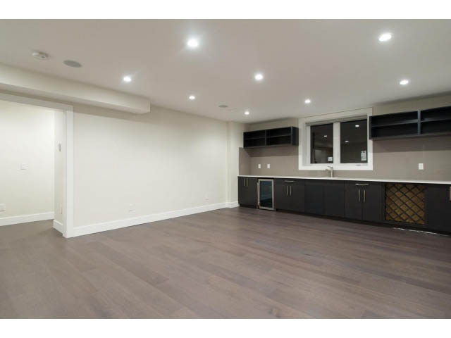Bright kitchen with dark cabinetry, hardwood floors, and modern lighting. - 3192 Beverley Cres, North Vancouver
