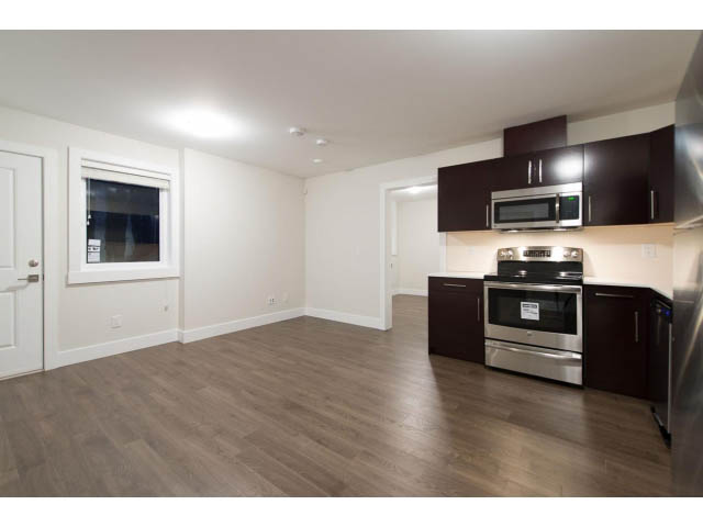 Bright kitchen with dark wood cabinets, stainless steel appliances, and hardwood floors. - 3192 Beverley Cres, North Vancouver