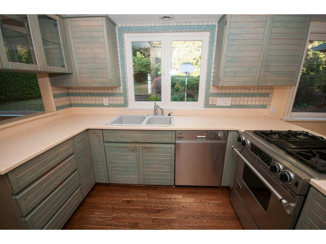 Bright kitchen with light green cabinets, white countertops, and hardwood floors. - 1145 Sutton Place, West Vancouver