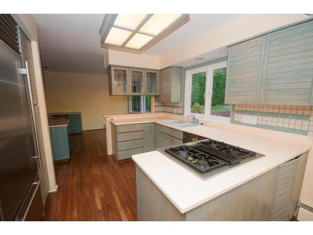 Bright kitchen with white countertops, hardwood floors, and a view of the garden. - 1145 Sutton Place, West Vancouver