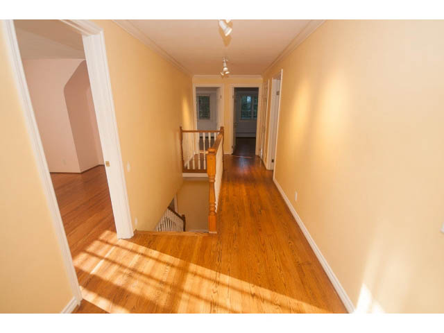 Bright hallway with hardwood floors and white trim, leading to a staircase. - 1145 Sutton Place, West Vancouver