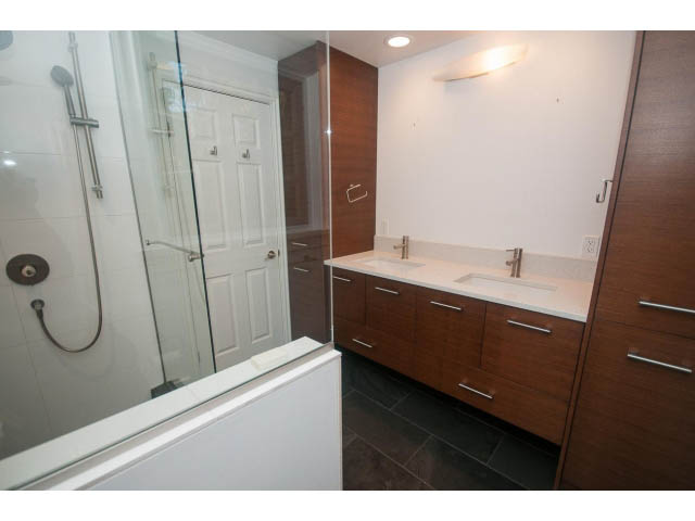 Modern bathroom with sleek white countertops and dark wood cabinetry. - 1145 Sutton Place, West Vancouver