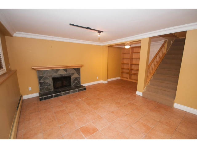 Living room with tiled floors, staircase, and fireplace. - 1145 Sutton Place, West Vancouver