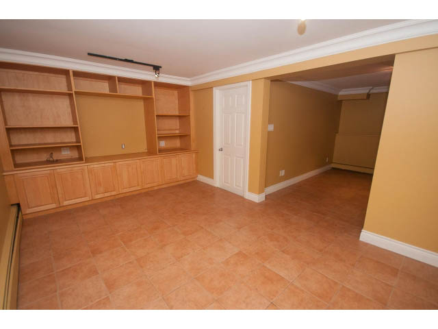 Spacious living room with built-in shelving and terracotta tile flooring. - 1145 Sutton Place, West Vancouver