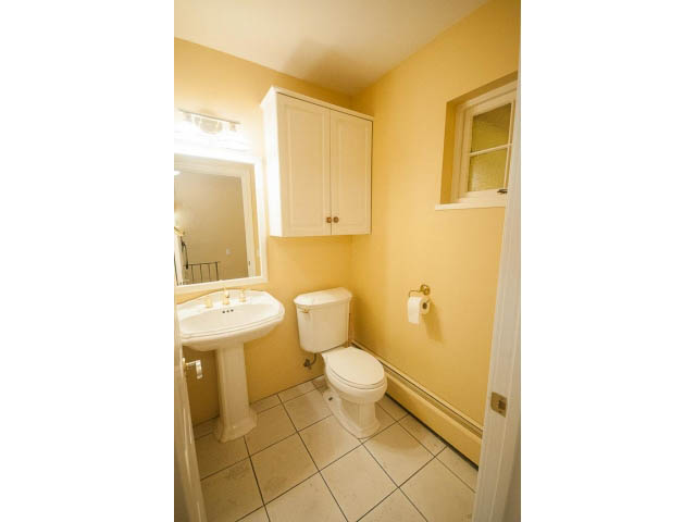 Bright bathroom with white cabinets and tiled floor. - 1145 Sutton Place, West Vancouver