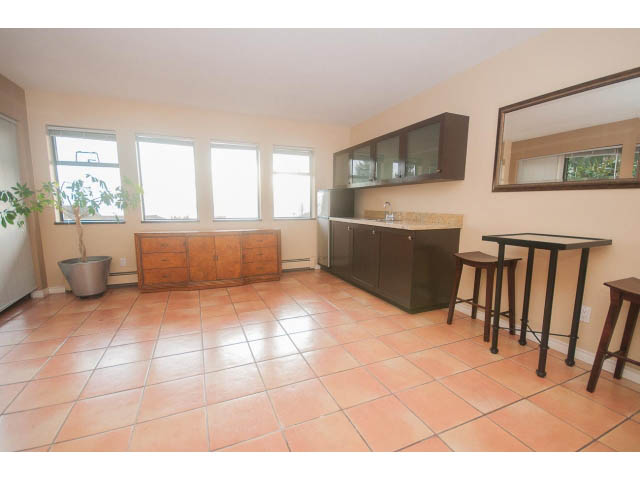 Bright kitchen with terracotta tile floors, modern cabinets, and a large window offering a view. - 4251A Rockbank, West Vancouver