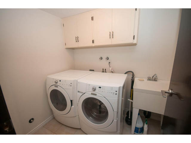 Laundry room with white cabinets, countertop, and washing machines. - 4251A Rockbank, West Vancouver