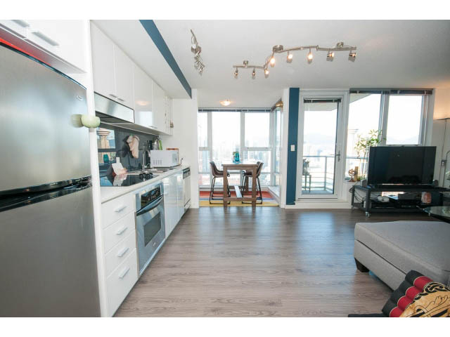 Bright kitchen with modern appliances and hardwood floors, leading to a living area with city views. - 3105 - 602 Citadel Parade, Vancouver Downtown
