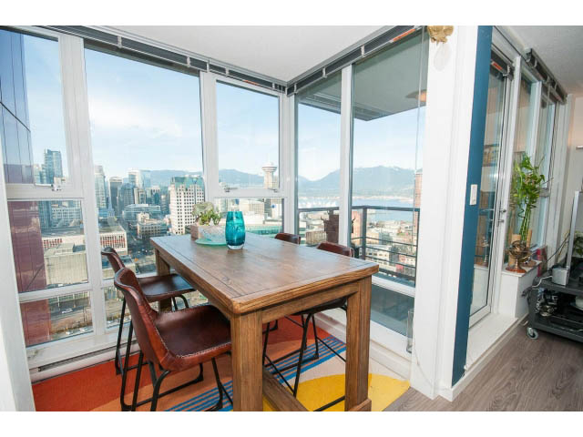 Bright dining area with city view, wooden table, and colorful rug. - 3105 - 602 Citadel Parade, Vancouver Downtown