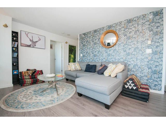 Furnished living room with blue floral wallpaper, gray sectional, and wooden floors. - 3105 - 602 Citadel Parade, Vancouver Downtown