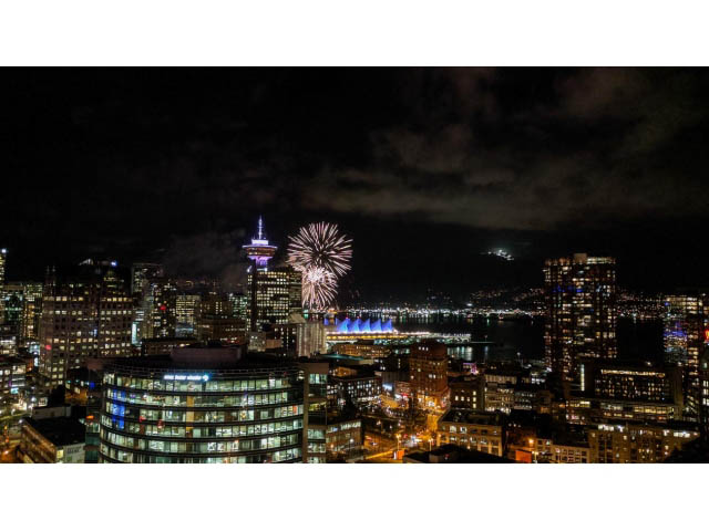 Bright living room with stunning city view and vibrant fireworks display. - 3105 - 602 Citadel Parade, Vancouver Downtown