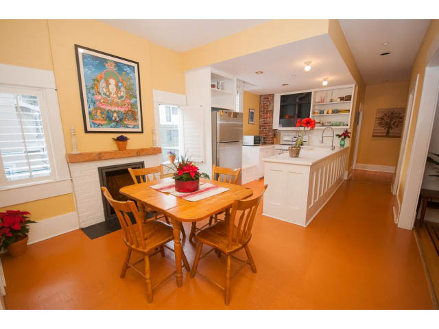 Bright kitchen with white cabinets, hardwood floors, and a colorful mural above the stove. - 1923 Waterloo St, Vancouver West Side