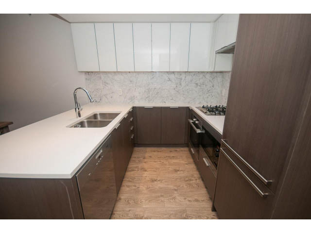 Bright kitchen with white countertops, wooden cabinets, and hardwood floors. - 203 - 110 Switchmen St, Vancouver East Side