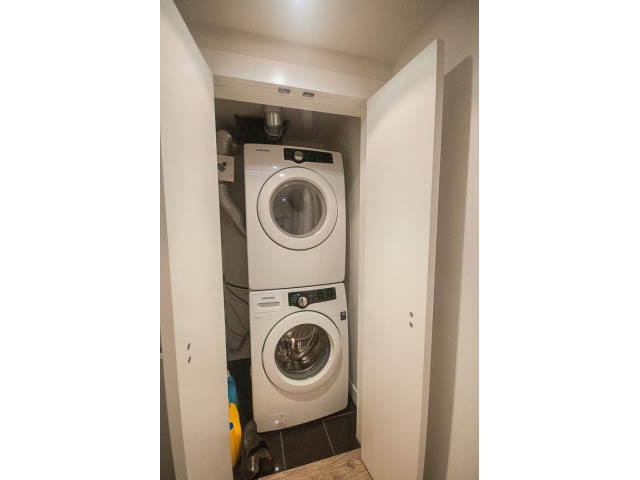 Laundry room with stacked washer and dryer, compact space, modern design. - 203 - 110 Switchmen St, Vancouver East Side