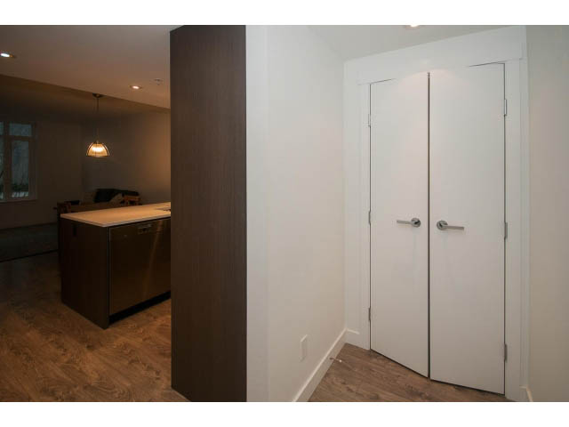 Bright kitchen with dark wood cabinets and white walls, featuring a countertop and hardwood floors. - 203 - 110 Switchmen St, Vancouver East Side