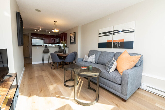 Furnished living room with hardwood floors, modern art, and a cozy corner sofa. - 2303 - 1328 West Pender Street, Vancouver Downtown