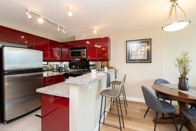 Modern kitchen with red cabinets, granite countertops, and stainless steel appliances. - 2303 - 1328 West Pender Street, Vancouver Downtown