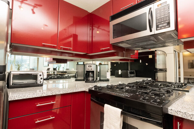 Bright kitchen with red cabinets, granite countertops, and stainless steel appliances, perfect for a cozy downtown condo.