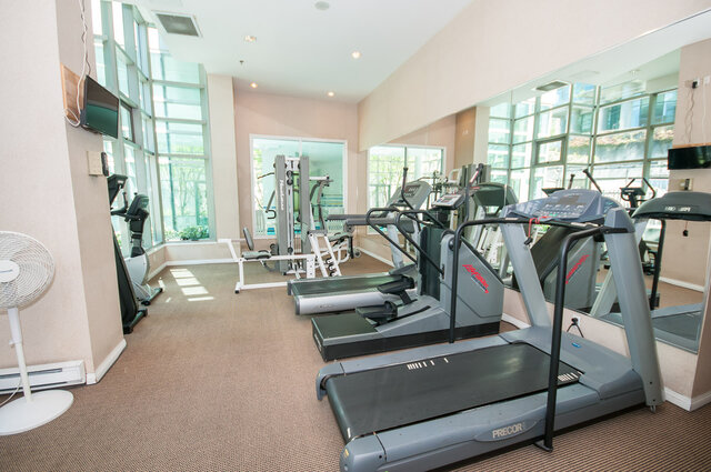 Spacious fitness room with modern treadmills and large windows, offering natural light and city views.