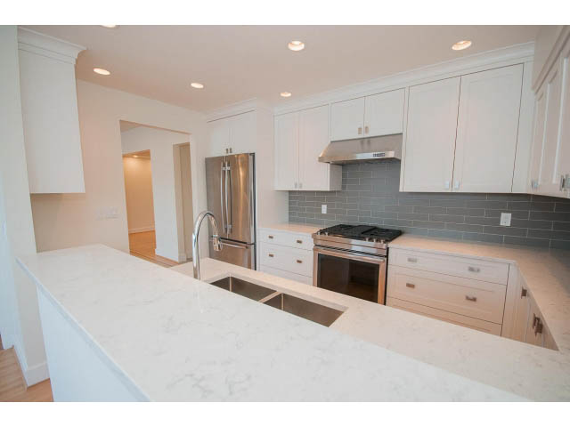 Bright kitchen with white cabinets, gray subway tile backsplash, and marble countertops. - 3655 Cameron Ave., Vancouver West Side