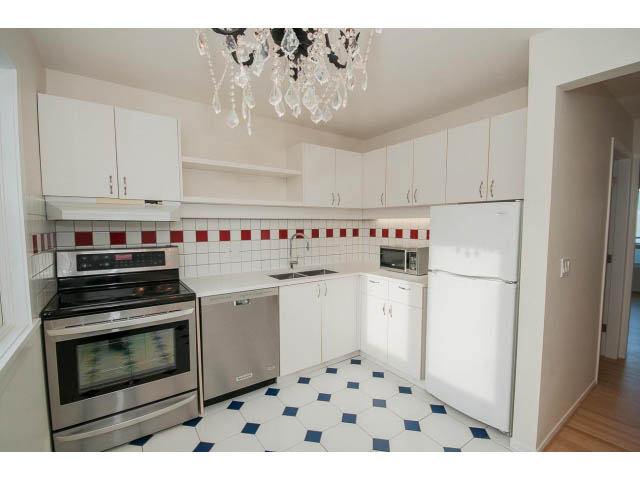 Bright kitchen with white cabinets, red and white tiled backsplash, and blue and white checkered floor. - 3655 Cameron Ave., Vancouver West Side