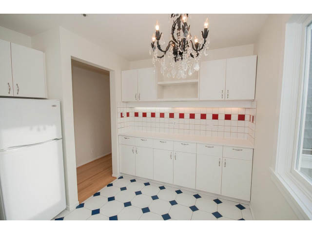 Bright kitchen with white cabinets, red-tiled backsplash, and checkered floor. - 3655 Cameron Ave., Vancouver West Side