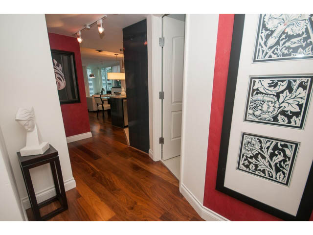 Furnished hallway with red accents, hardwood floors, and framed artwork. - 605 - 133 E Esplanade, North Vancouver