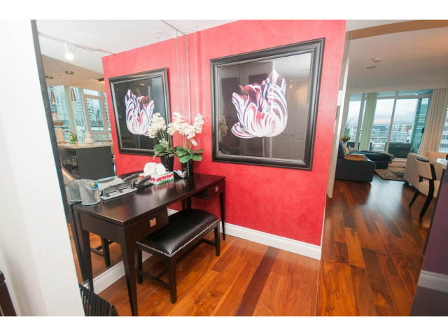 Furnished dining area with hardwood floors, red accent wall, and city view. - 605 - 133 E Esplanade, North Vancouver