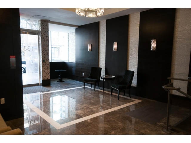 Spacious living room with marble countertops and black furniture. - 605 - 133 E Esplanade, North Vancouver