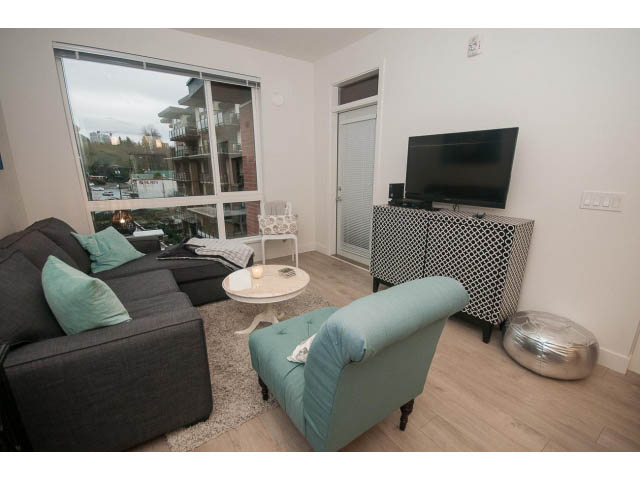 Furnished living room with city view, hardwood floors, and modern decor. - 416 - 733 West 3rd St, North Vancouver