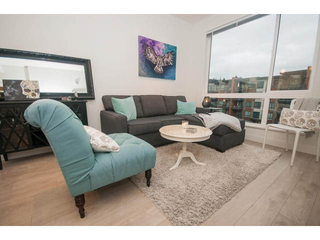 Furnished living room with hardwood floors, city view, and modern decor. - 416 - 733 West 3rd St, North Vancouver