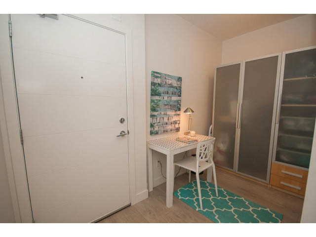 Bright den with hardwood floors, white walls, and a teal rug. - 416 - 733 West 3rd St, North Vancouver