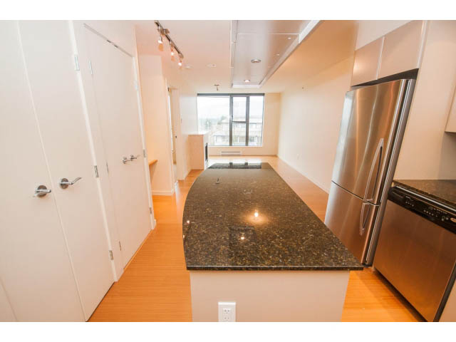 Bright kitchen with granite countertops and hardwood floors, featuring a city view. - 407 - 683 Victoria Park West, North Vancouver