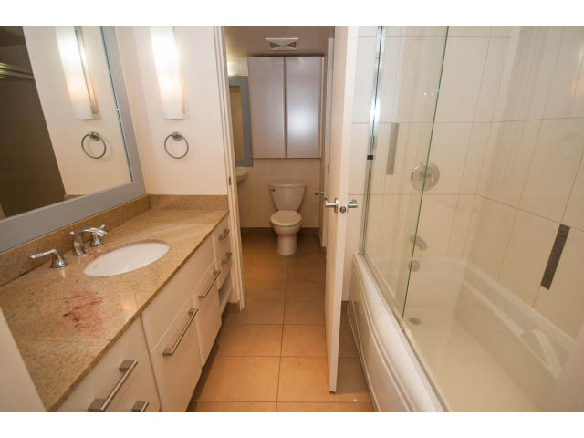Bright bathroom with granite countertops and a glass shower enclosure. - 407 - 683 Victoria Park West, North Vancouver