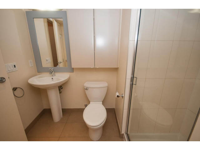 Compact bathroom with white fixtures and beige tiles. - 407 - 683 Victoria Park West, North Vancouver
