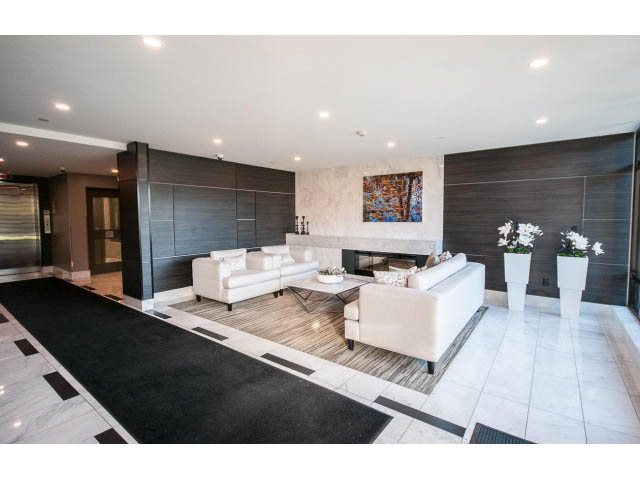 Spacious living room with modern furnishings, marble countertops, and hardwood floors. - 203 - 3825 Cate's Landing, North Vancouver