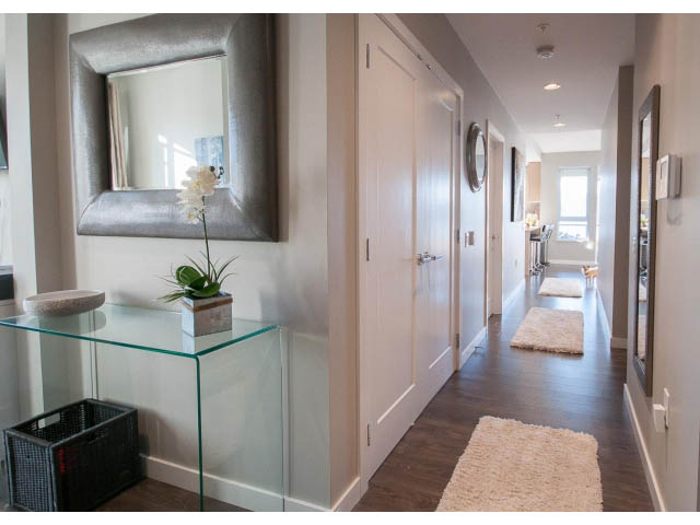Furnished hallway with glass shelves, modern decor, and hardwood floors. - 203 - 3825 Cate's Landing, North Vancouver